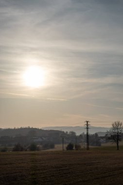 Açık arazisi olan huzurlu kırsal alan ve güneş sabah sisi altında uzak tepelerin üzerinden yükseliyor..