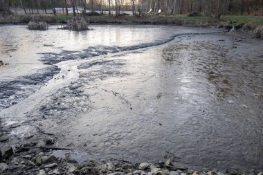 Yukarıdan bakıldığında kurumuş kamışlarla çamurlu gölet tabanından akan küçük bir dere..