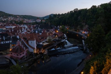 Aydınlatılmış evleri, sakin nehri, küçük barajı ve tarihi şehir manzarası olan eski şehrin akşam manzarası.