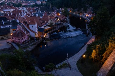Aydınlatılmış evleri, sakin nehri, küçük barajı ve tarihi şehir manzarası olan eski şehrin akşam manzarası.