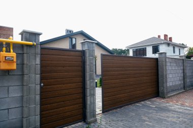 Evin avlusuna açılan kapı. Kapı kahverengidir. Yüksek kalite fotoğraf. Arka planda bir ev görülebilir. Kapının yanında sarı bir gaz sayacı var..