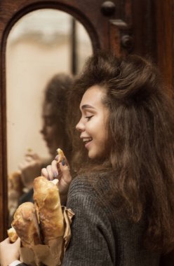 Masada oturup donut yiyen biri. Güzel bir kızın Fransız ekmeği vardır. Yumuşak ekmek yiyor ve hayattan zevk alıyor. Palto giyiyor, kıvırcık saçları var. Tahta bir masada oturuyor.