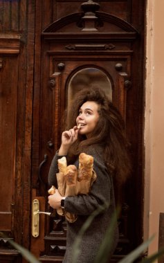 Masada oturup donut yiyen biri. Güzel bir kızın Fransız ekmeği vardır. Yumuşak ekmek yiyor ve hayattan zevk alıyor. Palto giyiyor, kıvırcık saçları var. Tahta bir masada oturuyor.