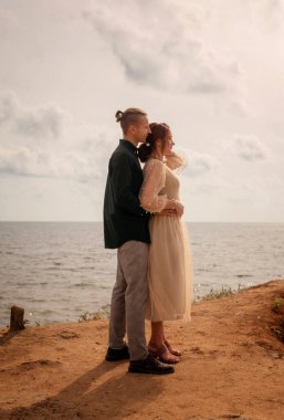 İki aşık denizin önündeki bir uçurumda dikiliyorlar. Denize bakıyorlar, bir adam bir kıza sarılıyor. Kız bej bir elbise giymiş, boyları çok uzun.