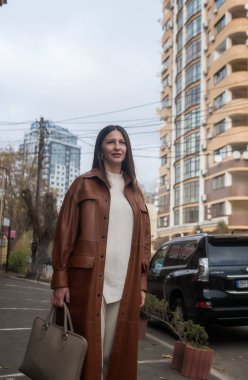 Şehrin iş bölgesinde 40 yaşın üzerinde zarif bir kadın yürüyor. O kahverengi bir ceket giyiyor. Elinde deri bir laptop çantası var. Sonbahar şehrinde mükemmel bir iş kadını.