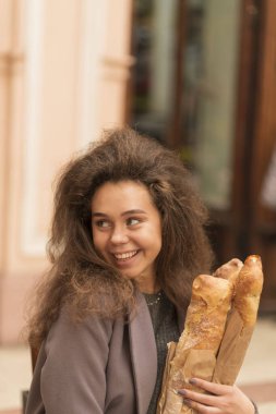 Caddedeki bir kafede elinde bir baget tutan güzel bir genç kadın. Kızların yüzüne yakın çekim yaptı, arkasını döndü ve başka tarafa baktı. Tatlı ve açık bir gülümsemesi var.. 
