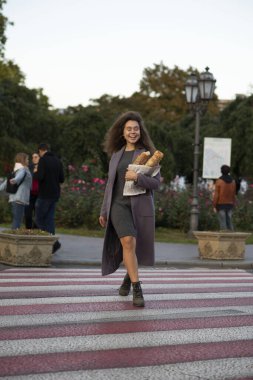 Kız elinde bir ekmek ekmeği tutuyor. Yaya geçidinde karşıdan karşıya geçiyor. O bir öğrenci, genç ve zayıf. Kameraya bakıyor, çok güzel bir gülümsemesi var..