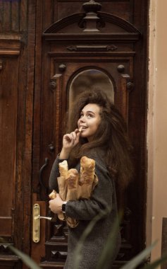 Masada oturup donut yiyen biri. Güzel bir kızın Fransız ekmeği vardır. Yumuşak ekmek yiyor ve hayattan zevk alıyor. Palto giyiyor, kıvırcık saçları var. Tahta bir masada oturuyor.