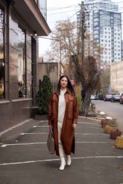 Şehrin iş bölgesinde 40 yaşın üzerinde zarif bir kadın yürüyor. O kahverengi bir ceket giyiyor. Elinde deri bir laptop çantası var. Sonbahar şehrinde mükemmel bir iş kadını.