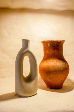 decorative handmade clay pottery on a shelf with lighting. close-up of natural pottery, eco-friendly, two items stand next to each other, this is a jug and a vase hard light clipart