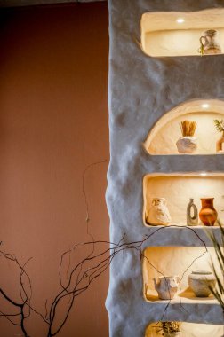 Dekoratif duvar, arka fonda el yapımı vazolar ve kemerler var. Bej rengi duvarda çiçekli vazolar var. Kemerler sıcak ışıkla aydınlatılır. boş sıcak kahverengi arkaplanın yanında.
