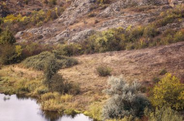 Fantastic autumn in a mountain canyon. Huge granite boulders. Aktovsky canyon in Ukraine with cliffs, forests and meadows, a mountain lake below. Bright yellow trees, meadow around the lake clipart