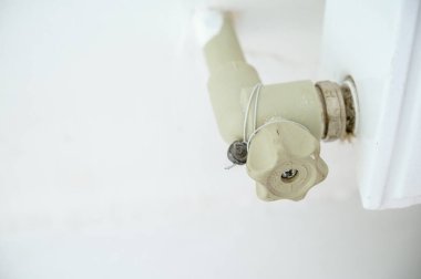 Isıtma sistemine uyan plastik bir kapakçığa yakın plan. Isıtma sistemli boru ve radyatör. Vanada bir mühür var. Musluk kapatıldı.. 