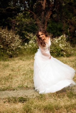 Çekici bir gelin çiçek açan ağaçların arasında zarif bir şekilde dans eder ve döner. Zarafet, romantizm ve zamansız cazibe yayıyor. Avrupa tarzı korseli yumuşak pembe gelinlik.