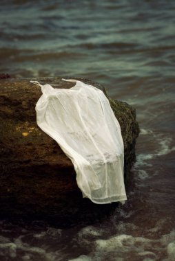 İnce beyaz elbise denizin etrafındaki bir kayanın üzerinde yatıyor. Elbise ıslak, ince kayışlarla. Yaz kıyafetleri ve dinlenme konsepti