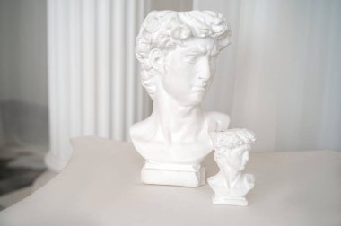 İç taraftaki güzel antik dekoratif heykelleri kapatın. İki alçı heykel antika stil masasının üzerinde duruyor. Beyaz şifon kumaş ve sütunlar