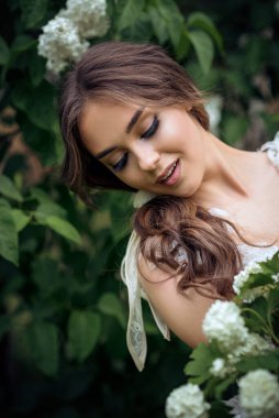 Çiçek açan ağaçların arasında genç ve güzel bir esmerin portresi. Uzun saçlı, şık bir tarzı var. Temiz cilt. Bahar ve parlak güzellik kavramı. 