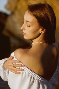 Beyaz elbiseli, kendine güvenen bir kadının zarif portresi, Yumuşak, Günışığı Ambiance 'daki Doğal Güzellik ve Duruşu Yakalıyor.