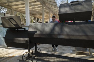 Odessa, Ukrayna - Nisan 05, 2025: Şehir sokak yemekleri festivali. Mangal yapan erkek aşçı. Büyük barbekü düzeneği.