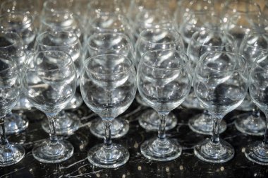 Gündüz vakti arka planda bir sürü boş temiz şarap kadehi. Şarap bardakları, bardaklar, bardaklar, sıralar, boş bardaklar, kahverengi, şeffaf, boş bardaklar, bir sürü. Siyah arka planda şarap bardakları yakın plan..