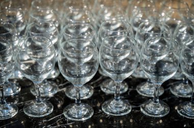 Gündüz vakti arka planda bir sürü boş temiz şarap kadehi. Şarap bardakları, bardaklar, bardaklar, sıralar, boş bardaklar, kahverengi, şeffaf, cam, bir sürü. Siyah arka planda şarap bardakları yakın plan..