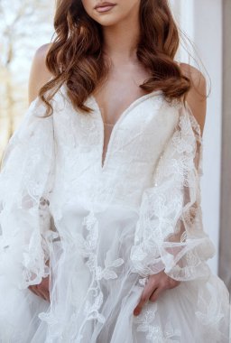 Huzurlu bir gelin zarifçe oturur, zarafet ve saflığı somutlaştırır. Beyaz elbisesi ve klasik saç stili sonsuz güzelliği vurguluyor. Yüksek kalite fotoğraf