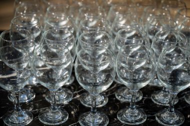 Gündüz vakti arka planda bir sürü boş temiz şarap kadehi. Şarap bardakları, bardaklar, bardaklar, sıralar, boş bardaklar, şeffaf bardaklar, boş bardaklar, bir sürü. Siyah arka planda şarap bardakları yakın plan..