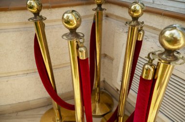 Kalabalığı kontrol etmek için kırmızı kadife ipli altın renkli metal ayaklıklar. Bir grup kırmızı kadife ip ve altın direkler, otel binasının yakınına kurulmayı bekliyorlar..