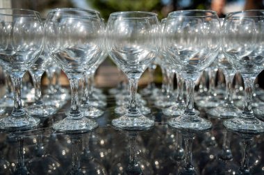 Gündüz vakti arka planda bir sürü boş temiz şarap kadehi. Şarap bardakları, bardaklar, bardaklar, sıralar, boş bardaklar, şeffaf, cam. Siyah arka planda şarap bardakları yakın plan..