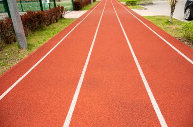 Parkta kırmızı yüzeyi olan koşu pisti. Kırmızı hat üzerinde beyaz çizgiler üzerinde parktan geçiyor.