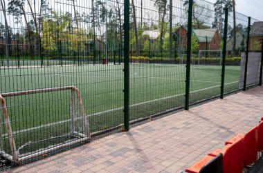 Futbol sahasında goller, çimlerin üzerinde beyaz çizgiler. Yeşil bir ağ ile çevrili, futbol sahasının etrafını çitle çevrili büyük hücreli demir bir ağ şeklinde. Yüksek kalite fotoğraf
