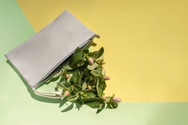 Sarı ve açık yeşil arka planda, kadınların beyaz kozmetik torbaları ve bahar elma dalları var. Kozmetik, bahar, tazelik kavramı..