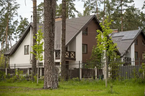 Yeni evin dış cephesi ve çatısı kahverengiydi. Köyde çam ormanlarıyla çevrili beyaz evler. Evin etrafında çeşitli ağaçlar var. Doğa koruma alanı, orman, park.