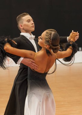 Dans pistinde standart bir Avrupa programında dans eden bir çift. Paltolu genç bir adam, siyah beyaz elbiseli ve beyaz ayakkabılı bir kız. Çift vals yapıyor.