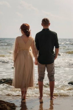 Güneşli bir günde, deniz kenarında genç, sevgi dolu ve romantik bir çift. Onlar ufukta görünmektedirler. Yeni evliler el ele tutuşuyor. Suda yalınayak duruyorlar, deniz esintisi var.