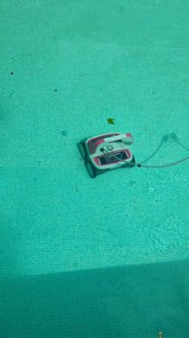 Havuz temizleyici robot güneşli bir yaz gününde temiz turkuaz suyla havuzu temizler. Oteller, tatil köyleri ve kır evleri için havuz temizleme konsepti. Yüksek kalite 4k görüntü