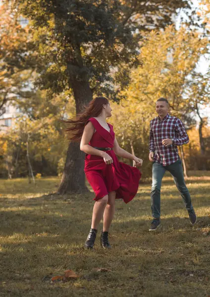 Genç aşık çift sonbahar parkında dinleniyor. Kaçıyorlar, eğleniyorlar ve gülüyorlar. Kırmızı elbiseli kız, altın sonbahar arka planına karşı. Romantizm kavramı, aşık olmak.. 