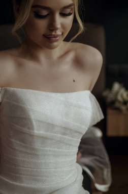 Gelin derisi ve omuzlarının yakın çekimi. Güzel gelin portresi, lüks gelinlik içinde, dantelli ve karanlık iç kısımlarında kristaller..