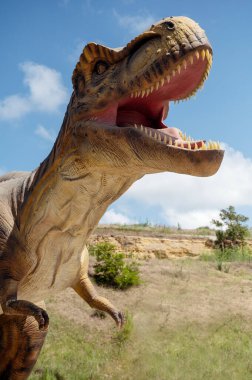 Yapay dinozor tyrannosaurus, gökyüzüne ve kayalara karşı dev bir dinozor heykeli. Dinozor ağzını açtı. Kopyalama alanı olan. Yırtıcı tiranozor figürüne sahip Jurassic Park. 