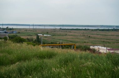Resmedilmeye değer kırsal alanlar, geniş çayırlar ve ön planda ağaçlar ilkbahar, mavi gökyüzü ile yaz yeşil alanlar, ufukta göl. Altyapısı olan vadideki köy.
