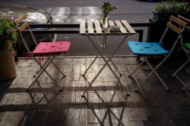 Sabahları sokak kafesi. Masada renkli sandalyeler ve yabani çiçekler olan boş bir teras. Masalı teras Avrupa şehrinde ziyaretçileri bekliyor. Yüksek kalite fotoğraf