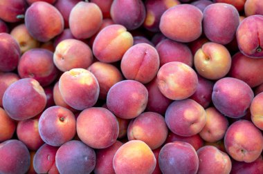 Taze şeftaliler, açık hava pazarında ahşap bir sandıkta bir araya toplanır. Canlı renkleri ve dokuları sergilenir. Yüksek kalite fotoğraf