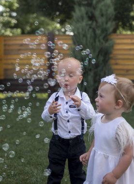 Erkek, kız ve baloncuklarla bahçede, arka bahçede oynamak ya da mutlulukla park etmek, aile ya da kardeşlerle. Çocuklar, sabun köpüğü oyunu ve çocuklukta eğlenceli, gençlik ve yaz güneşinin bayramında