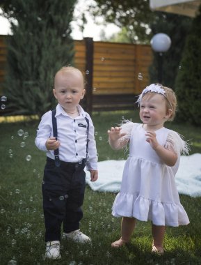 Giyinip kuşanmış şirin kız ve erkek çocukları sabun köpüğü görünce seviniyor ve şaşırıyorlar. Bahçede, bir sabun köpüğü gösterisine katılıyorlar, ailelerinin, kardeşlerinin, kız kardeşlerinin keyfini çıkarıyorlar.