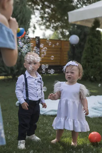 Erkek, kız ve baloncuklarla bahçede, arka bahçede oynamak ya da mutlulukla park etmek, aile ya da kardeşlerle. Çocuklar, sabun köpüğü oyunu ve çocuklukta eğlenceli ve tatilde yaz güneşi.