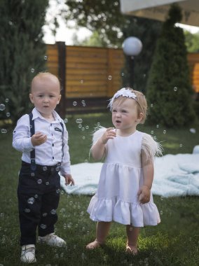 Giyinip kuşanmış şirin kız ve erkek çocukları sabun köpüğü görünce seviniyor ve şaşırıyorlar. Bahçede, dışarıda bir sabun köpüğü gösterisine katılıyorlar. Çocuklar sabun köpüğüyle oynar ve çocuklukta eğlenirler.