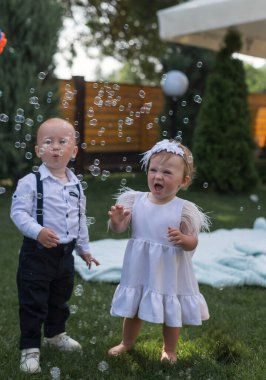 Giyinip kuşanmış şirin kız ve erkek çocukları sabun köpüğü görünce seviniyor ve şaşırıyorlar. Bahçede, bir sabun köpüğü gösterisine katılıyorlar, ailelerinin, kardeşlerinin, kız kardeşlerinin keyfini çıkarıyorlar.. 