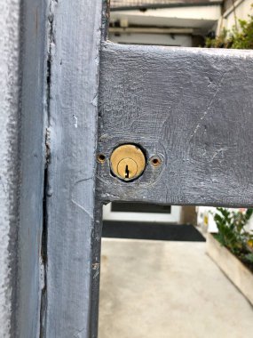 Close-up of a brass lock embedded in a weathered gray metal door, showcasing industrial textures and signs of wear over time. clipart