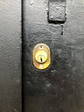 Modern minimalizmi kentsel endüstriyel estetikle birleştiren desenli siyah metal bir kapının pirinç kilidi..