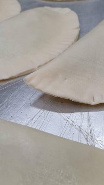 Close-up image of raw dough pieces arranged on a metal surface, showing the texture and preparation of the dough before baking. clipart